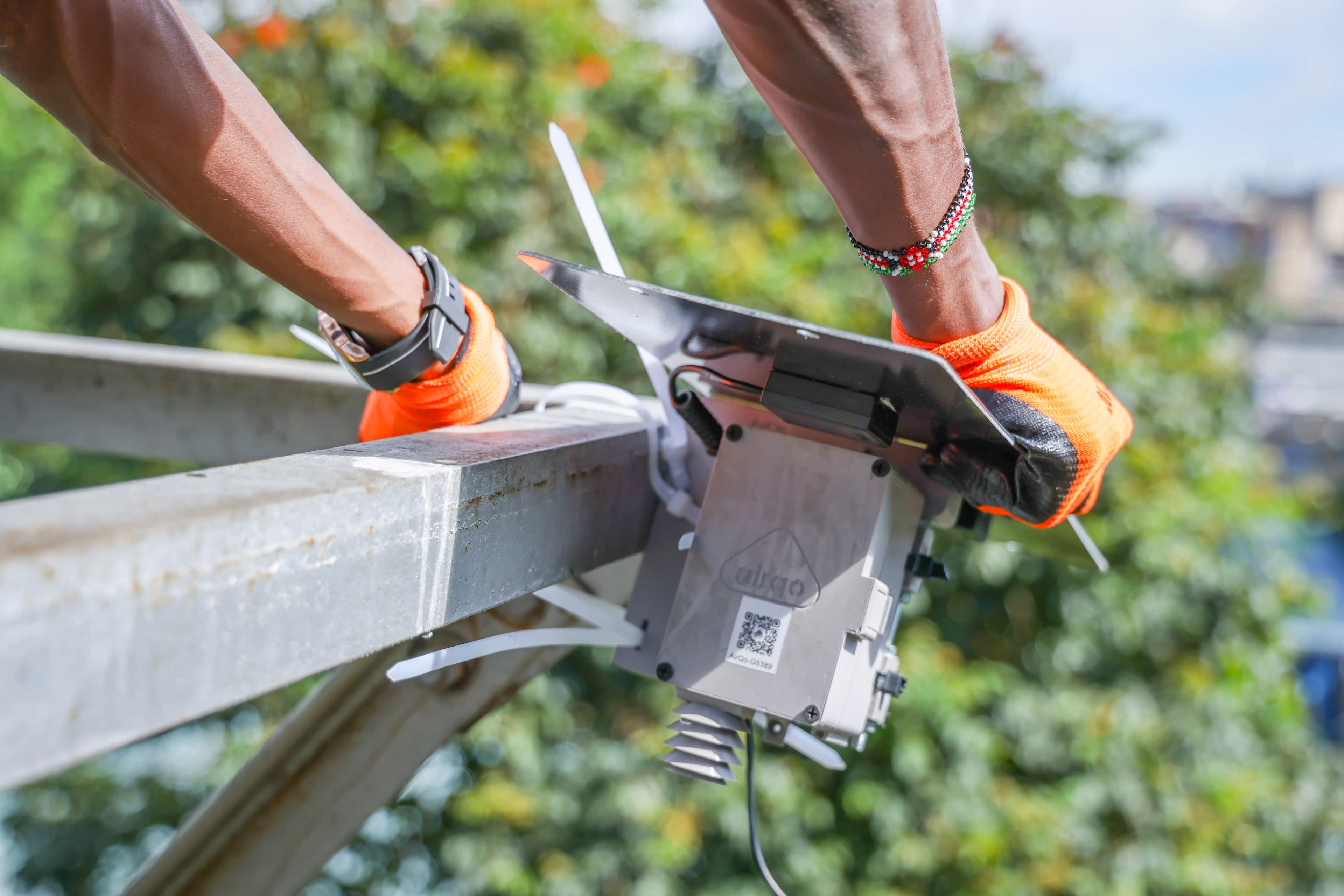 Technician installing a sensor on a rooftop wearing a white hard hat